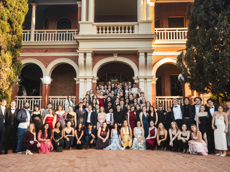 Students standing outside college building in formal attire.